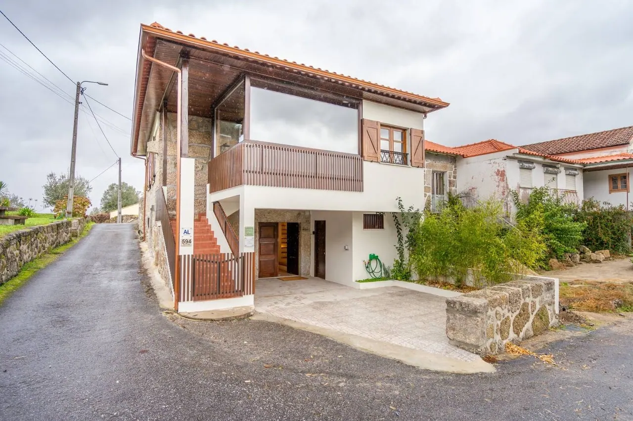 Fachada da moradia em pedra e madeira vista do caminho