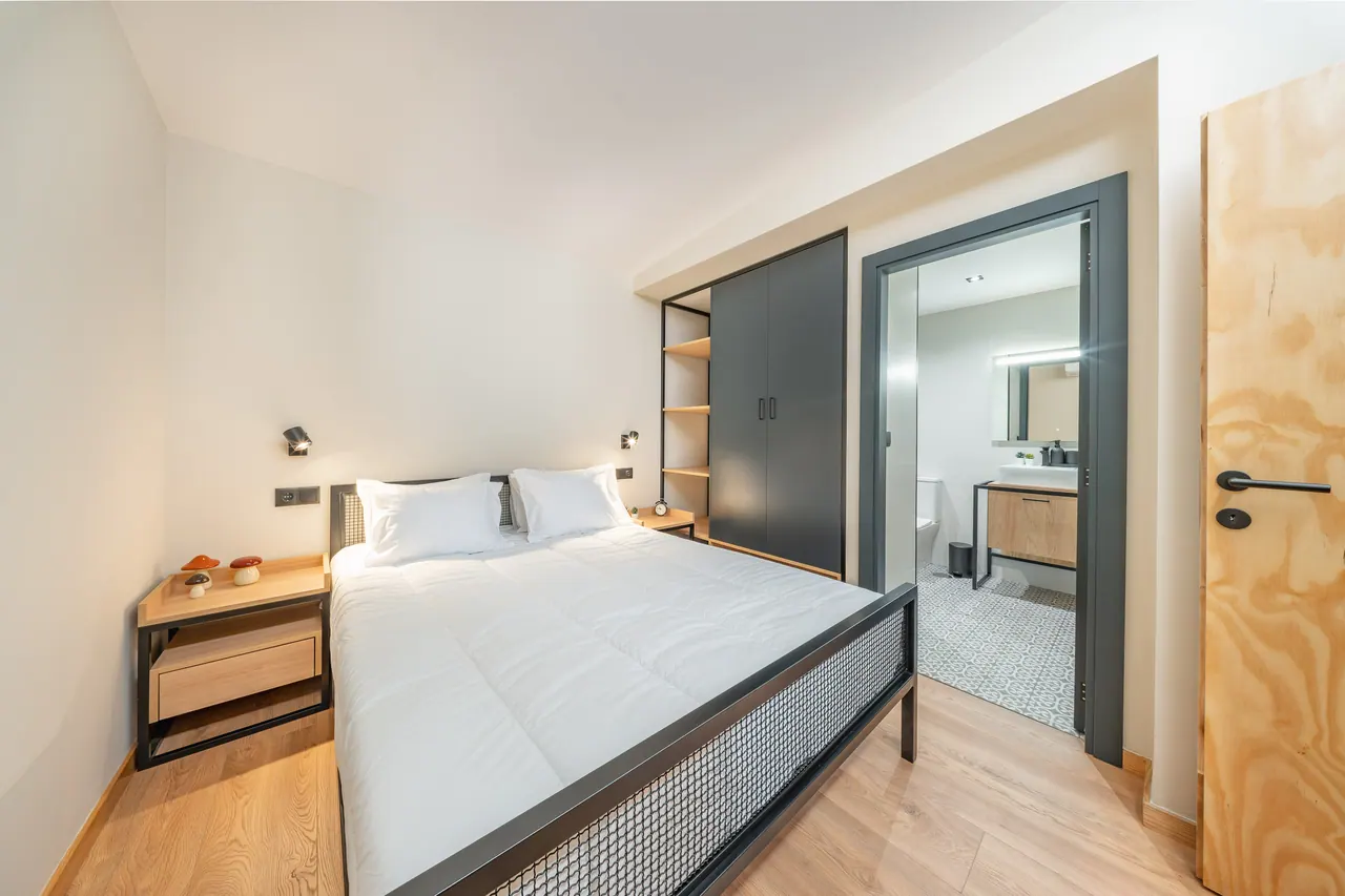 Quarto de casal com cama em estrutura metálica e janela alta