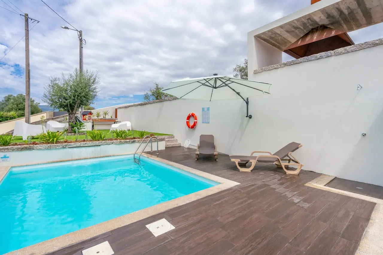 Espreguiçadeiras e chapéu de sol no deck junto à piscina privada