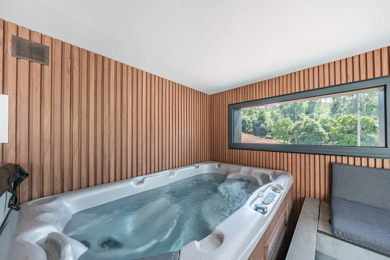 Jacuzzi privado interior revestido a madeira, com janela para a paisagem