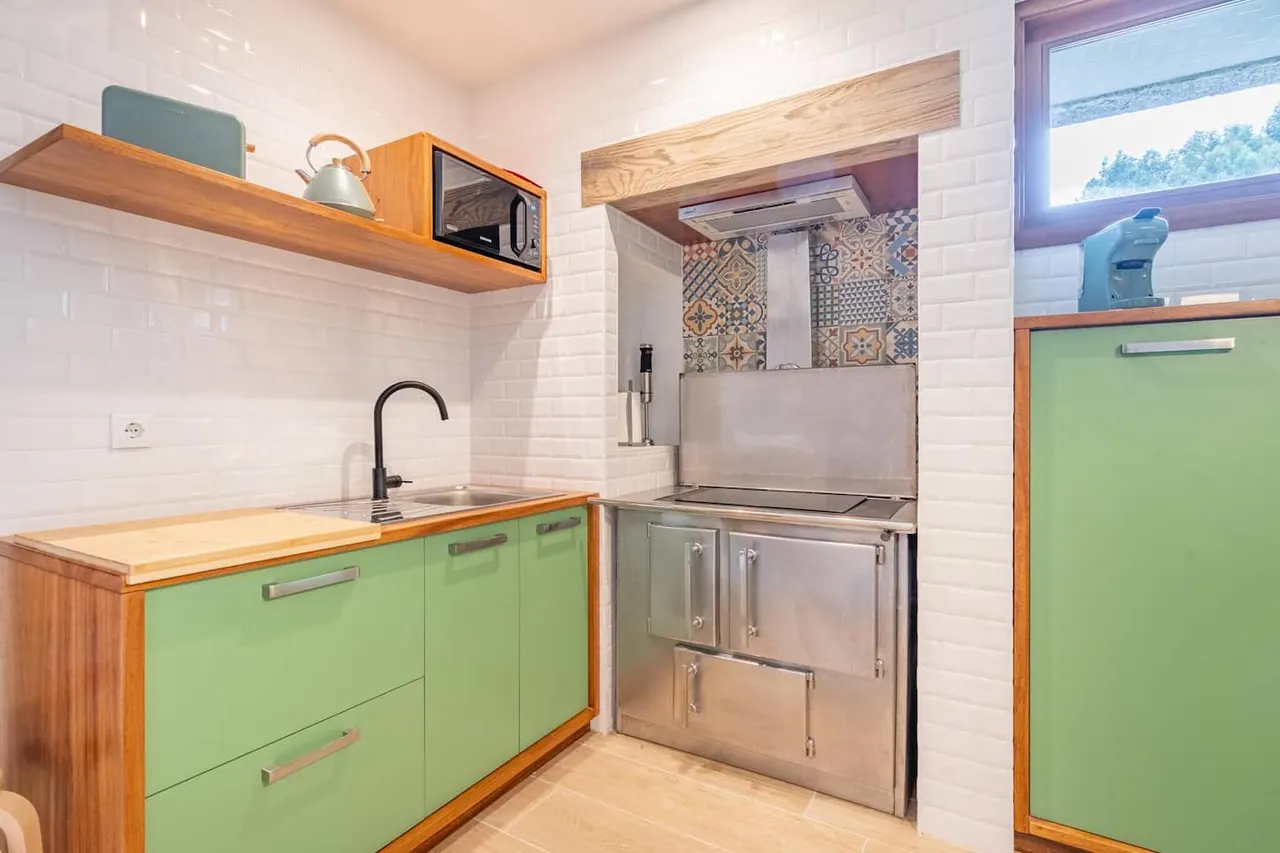 Cozinha verde equipada com bancada em madeira e azulejo decorativo