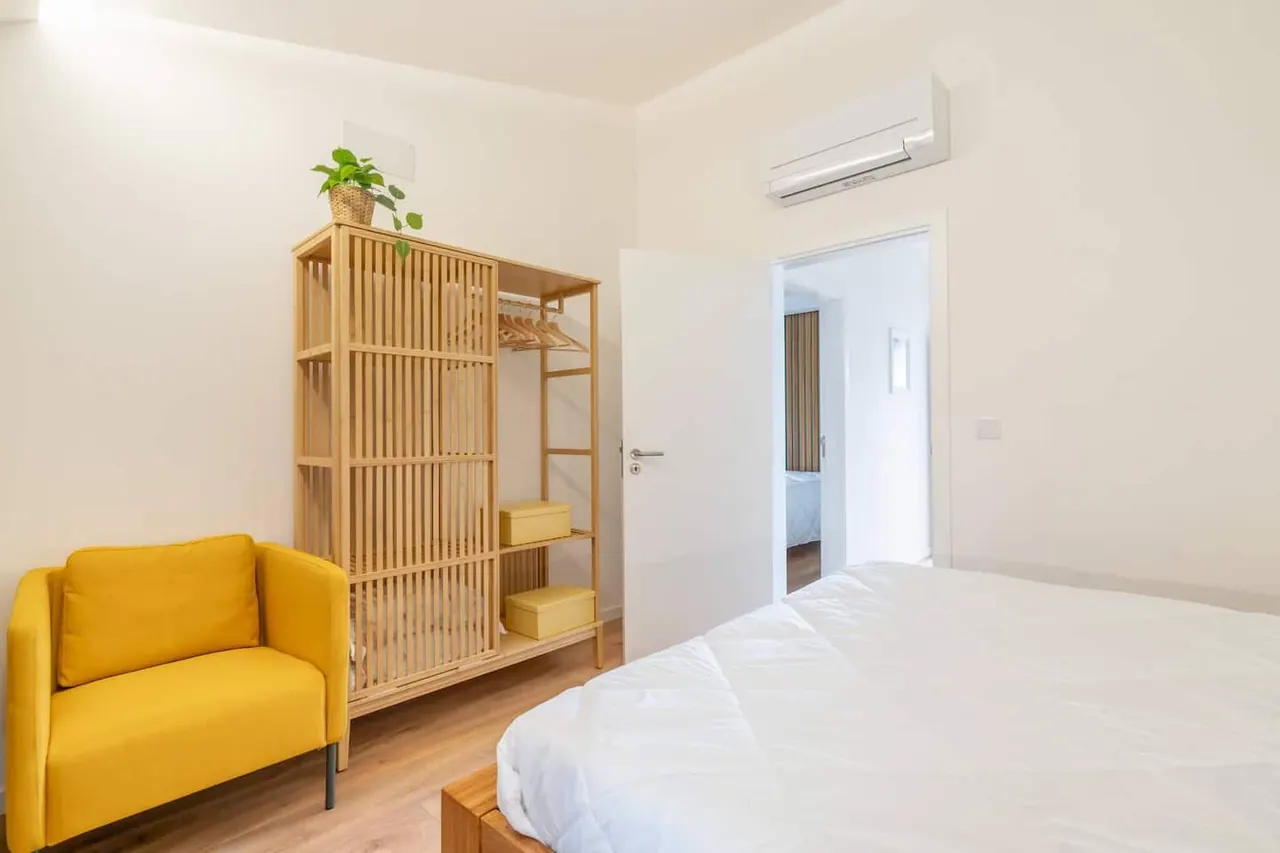 Quarto com poltrona amarela e estante em ripado de madeira